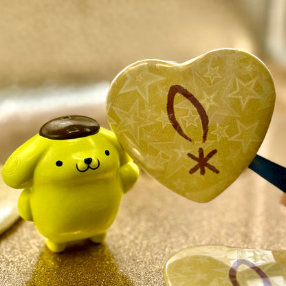 Heart-shaped button featuring Pompompurin from Kitschy Bits Co., with a cute Pompompurin character design on a hole button.